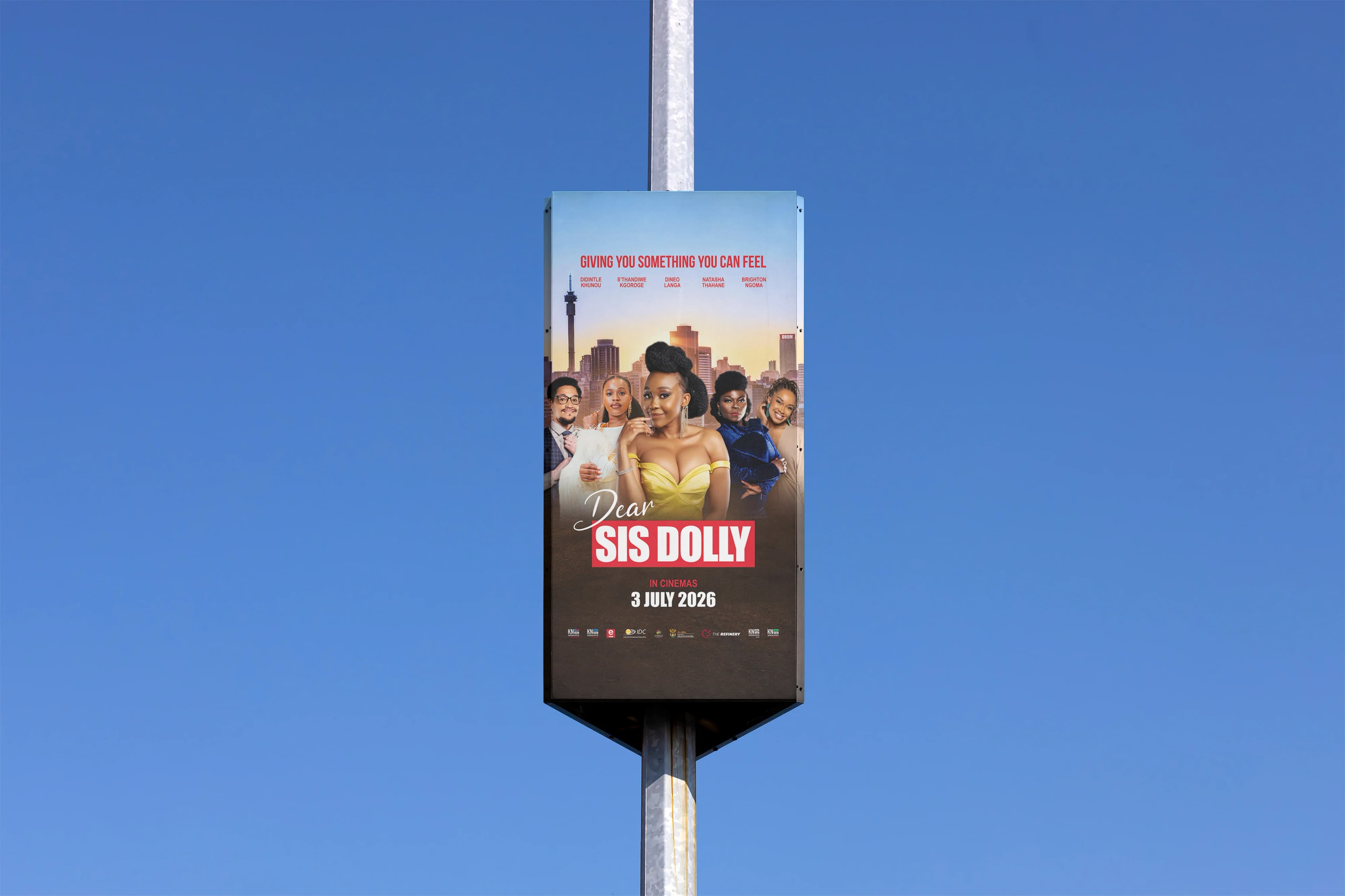 Dear Sis Dolly campaign poster presented on a pole-mounted street sign against a clear blue sky.