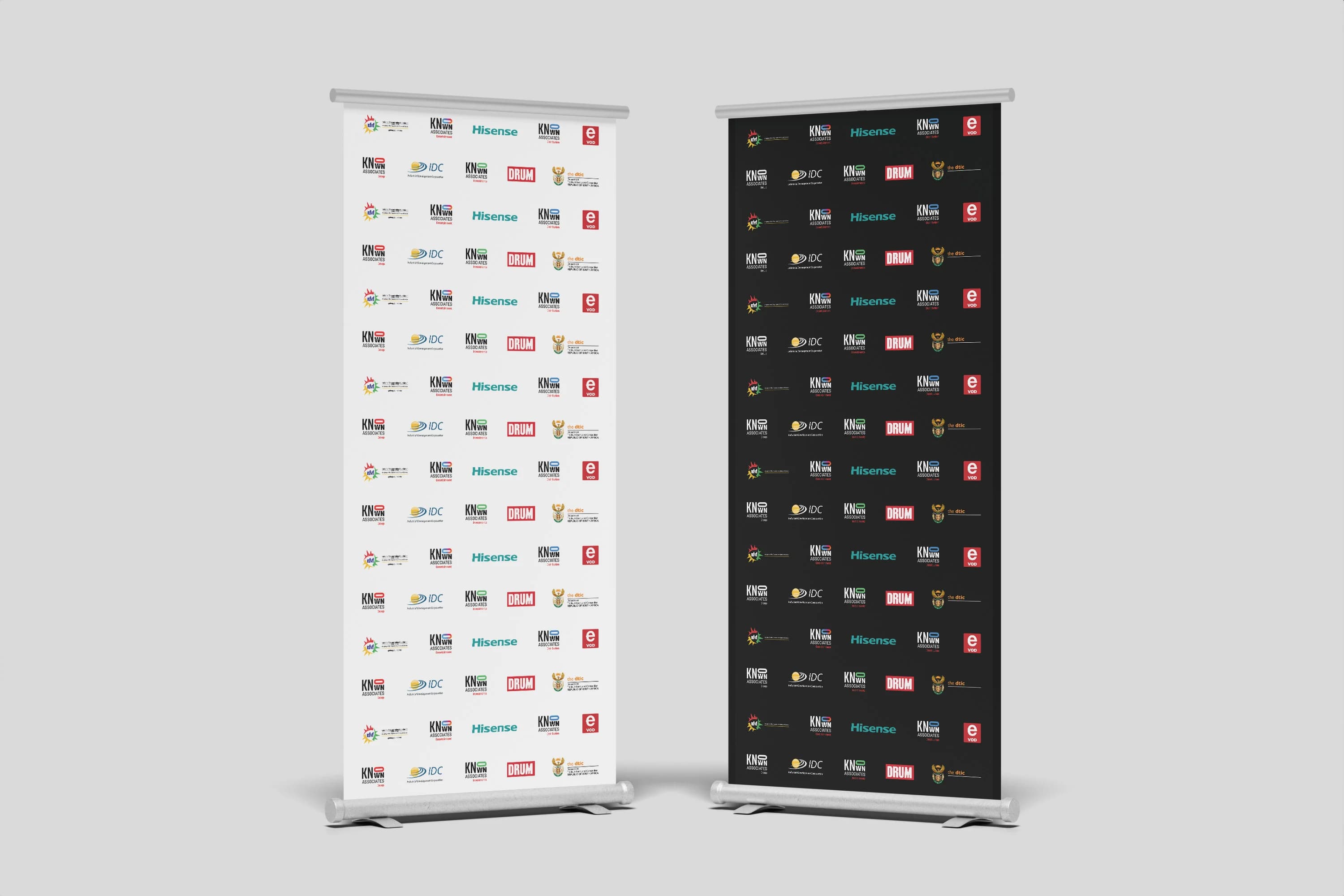 Two Dear Sis Dolly pull-up banners presented side by side, one light and one dark, tiled with the campaign's partner and sponsor logos.